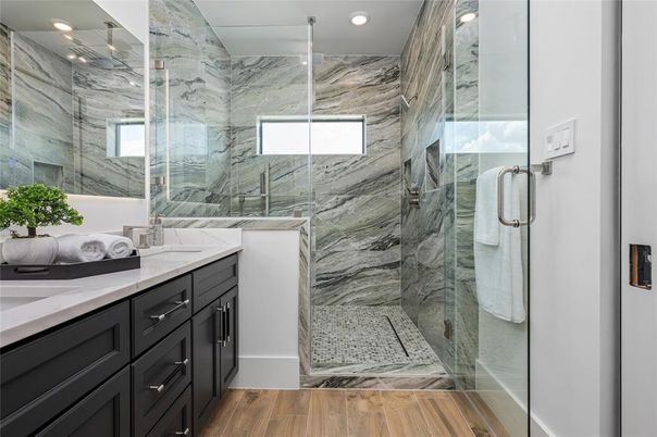 Bathroom, Dual Sink Vanities, Glass Shower, Interior, Marble Walls, Recessed Lighting, Wood Texture Flooring