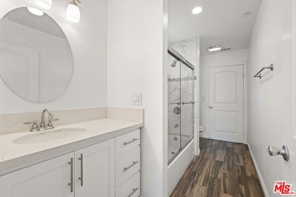 Bathroom, Dual Sink Vanities, Glass Shower, Interior, Marble Walls, Recessed Lighting, Wood Texture Flooring