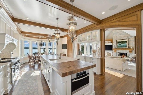 Chandelier, Dining room, Fireplace, Interior, Kitchen, Living room, Pendant Lights, Recessed Lighting, Stainless Steel Appliances, Stone Walls, Wooden Beams, Wood Texture Flooring