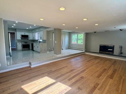 Empty room, Fireplace, Interior, Kitchen, Recessed Lighting, Stainless Steel Appliances, Wood Texture Flooring