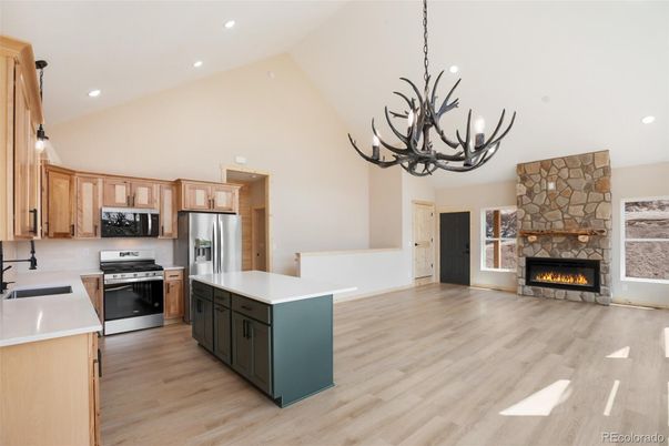 Chandelier, Fireplace, Interior, Kitchen, Pendant Lights, Recessed Lighting, Stainless Steel Appliances, Stone Walls, Wood Texture Flooring