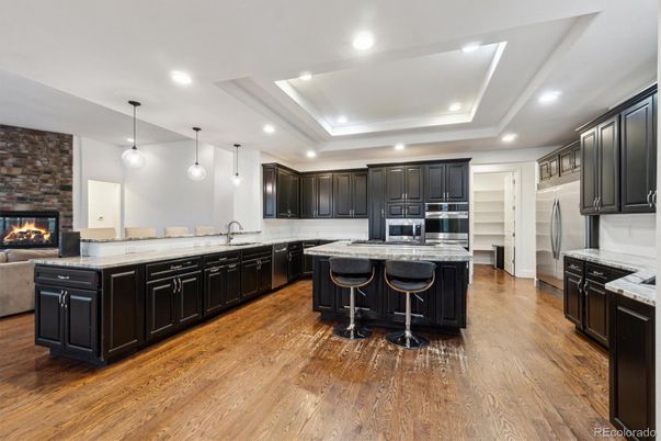 Fireplace, Interior, Kitchen, Pendant Lights, Recessed Lighting, Stainless Steel Appliances, Stone Walls, Wood Texture Flooring