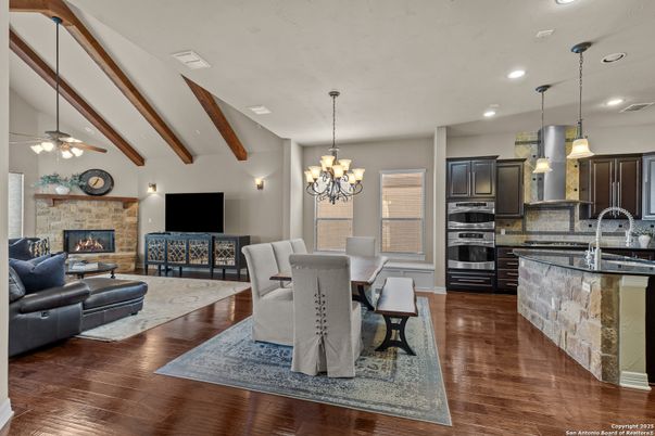 Chandelier, Dining room, Fireplace, Interior, Kitchen, Living room, Pendant Lights, Recessed Lighting, Stainless Steel Appliances, Stone Walls, Wooden Beams, Wood Texture Flooring