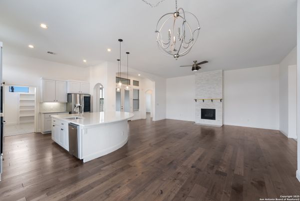 Chandelier, Empty room, Fireplace, Interior, Kitchen, Pendant Lights, Recessed Lighting, Stainless Steel Appliances, Stone Walls, Wood Texture Flooring