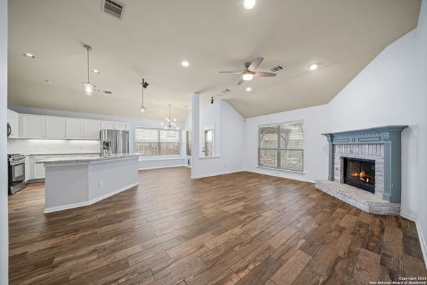 Empty room, Fireplace, Interior, Kitchen, Pendant Lights, Recessed Lighting, Stainless Steel Appliances, Wood Texture Flooring