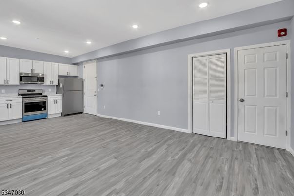 Empty room, Interior, Kitchen, Recessed Lighting, Stainless Steel Appliances, Wood Texture Flooring