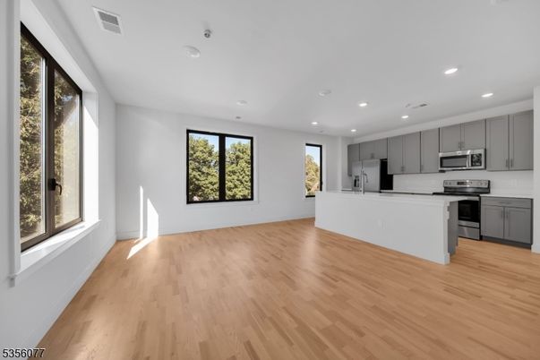 Empty room, Interior, Kitchen, Recessed Lighting, Stainless Steel Appliances, Wood Texture Flooring